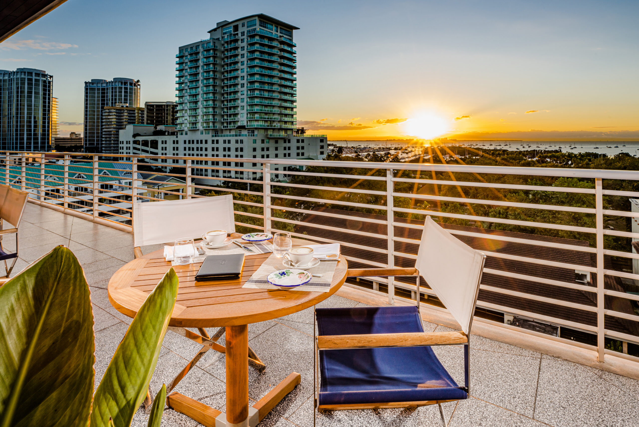 external shot of table and chairs on balcony overlooking sunset.