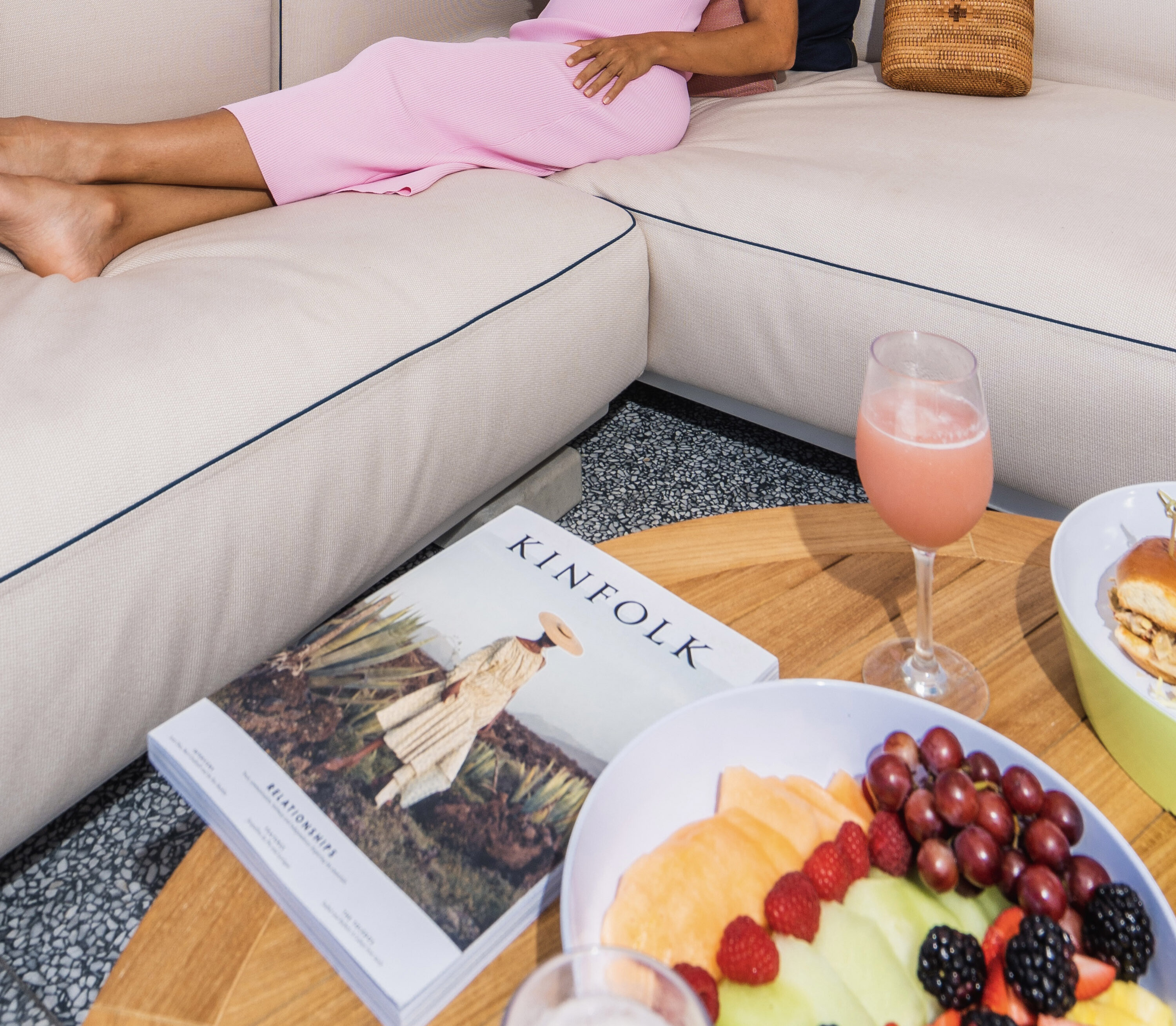 external shot of woman in cabana reclining with fruit and magazine on the table